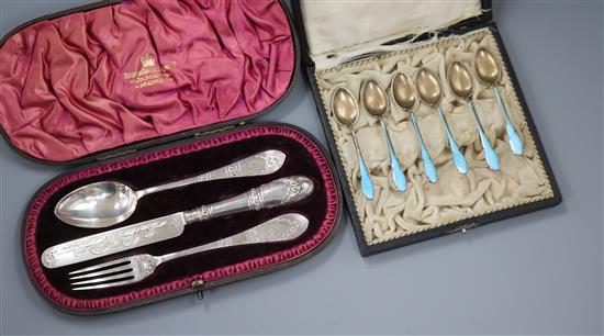 Two cased sets - six white metal and enamel teaspoons and a Victorian three piece silver Christening set.